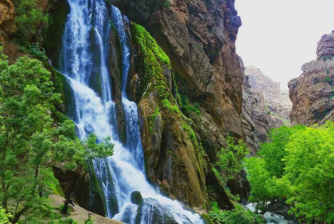 نمای کلی از آبشار بلند و خروشان آب سفید الیگودرز در میان صخره‌های مرتفع زاگرس