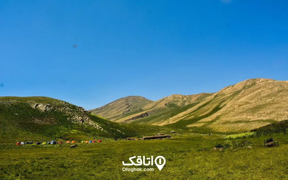 نمای کلی از ییلاق لپاسر رامسر با کلبه‌های سنگی در میان چمنزار کوهستانی